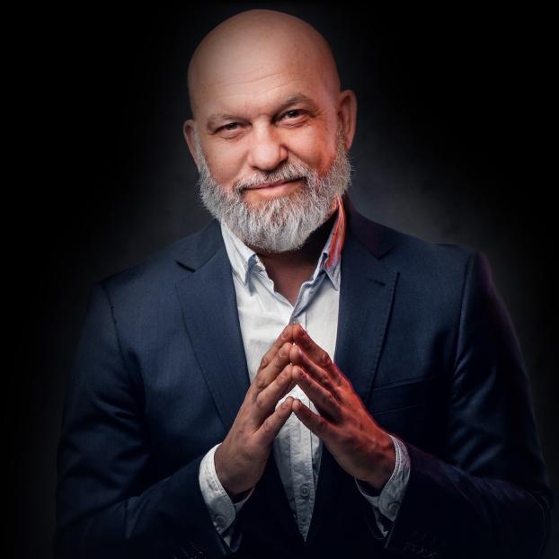 Studio headshot portrait of a bald man with a gray beard