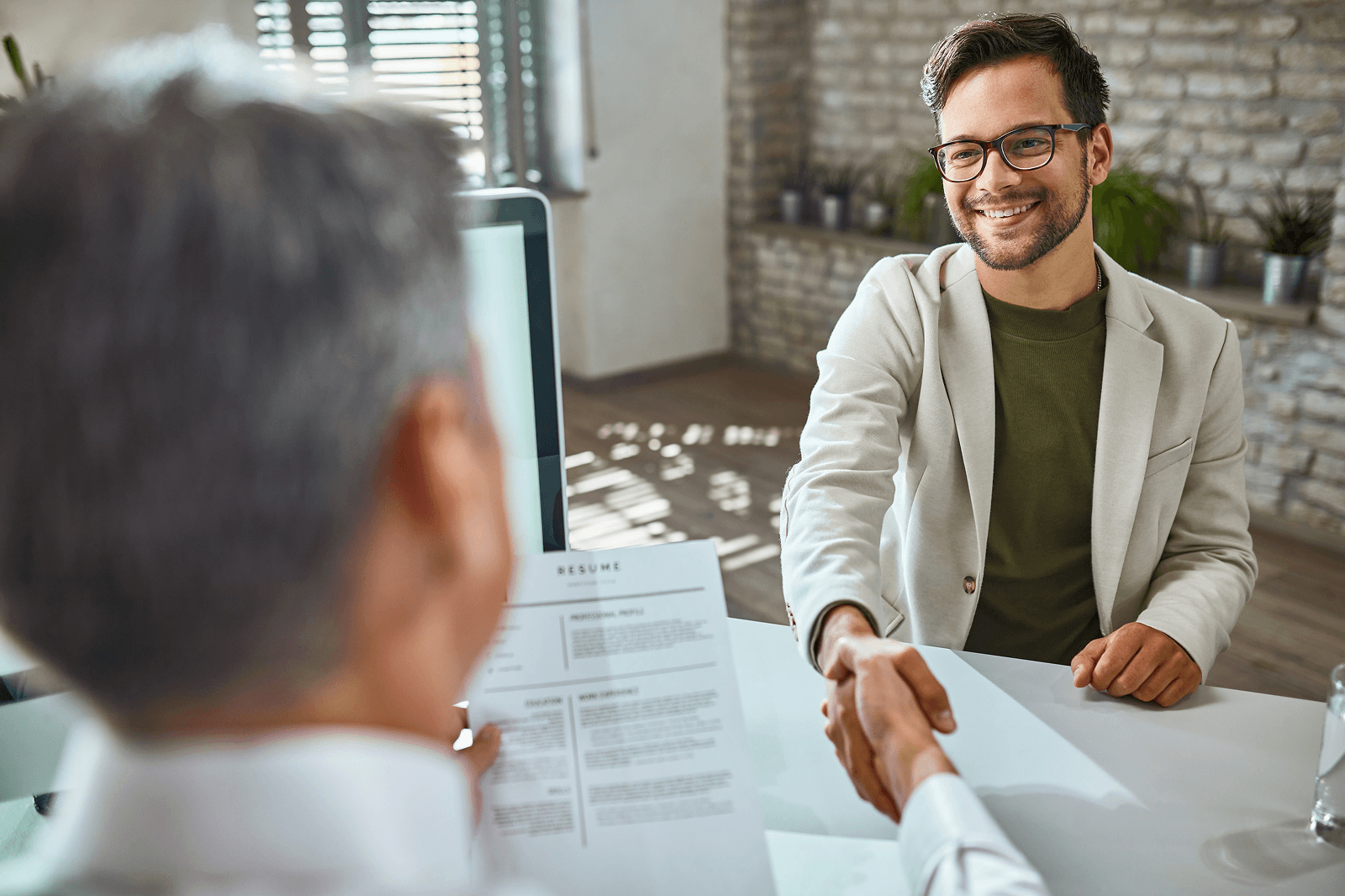 Photo of a job interview handshake with a resume on the table