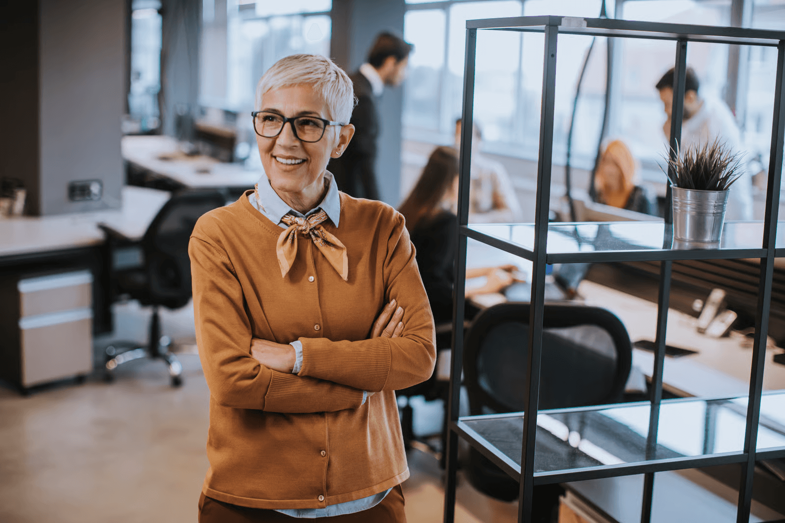 Photo of an older businesswoman with arms crossed smiling in an office