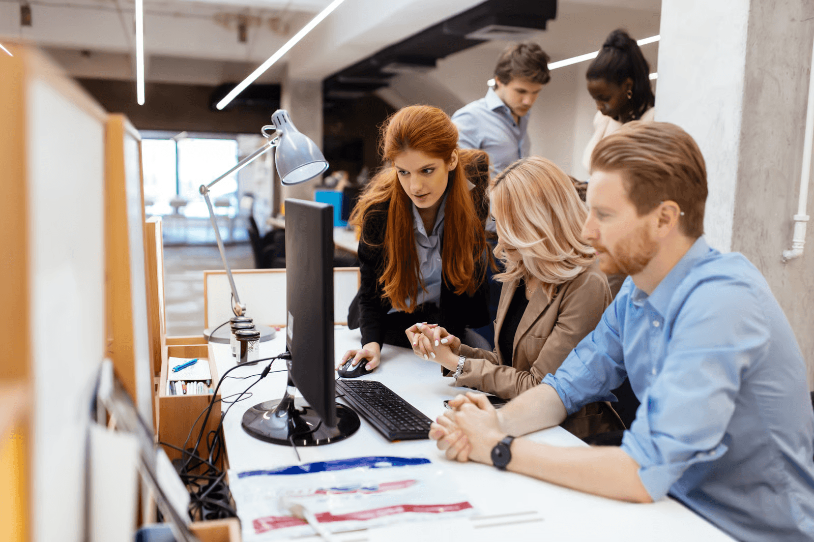 Photo of three coworkers looking at a desktop monitor together