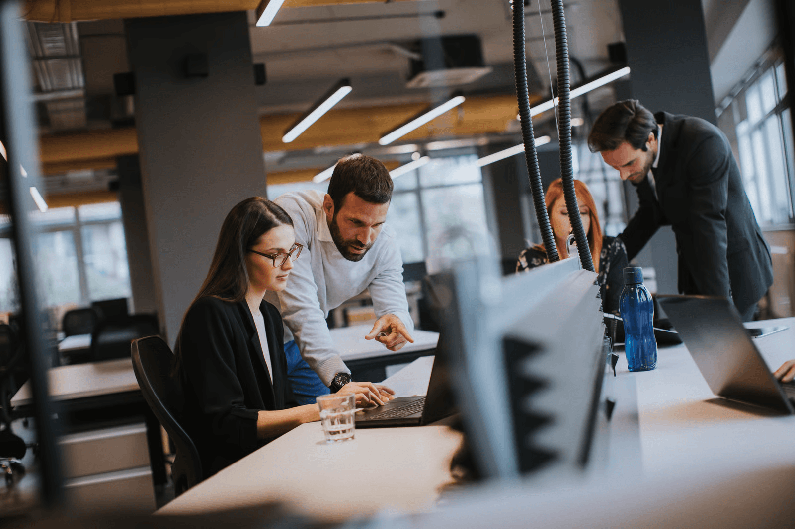 Photo of a man pointing at a colleague's laptop screen in a coworking space