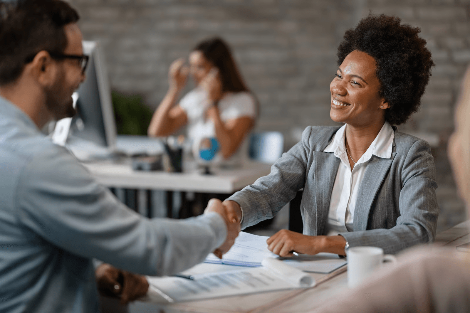 Photo of a businesswoman in a gray suit shaking hands in an office