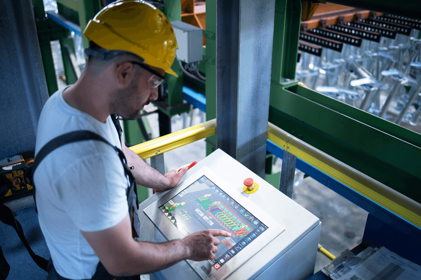 Photo of a factory worker in a hard hat using a touchscreen control panel