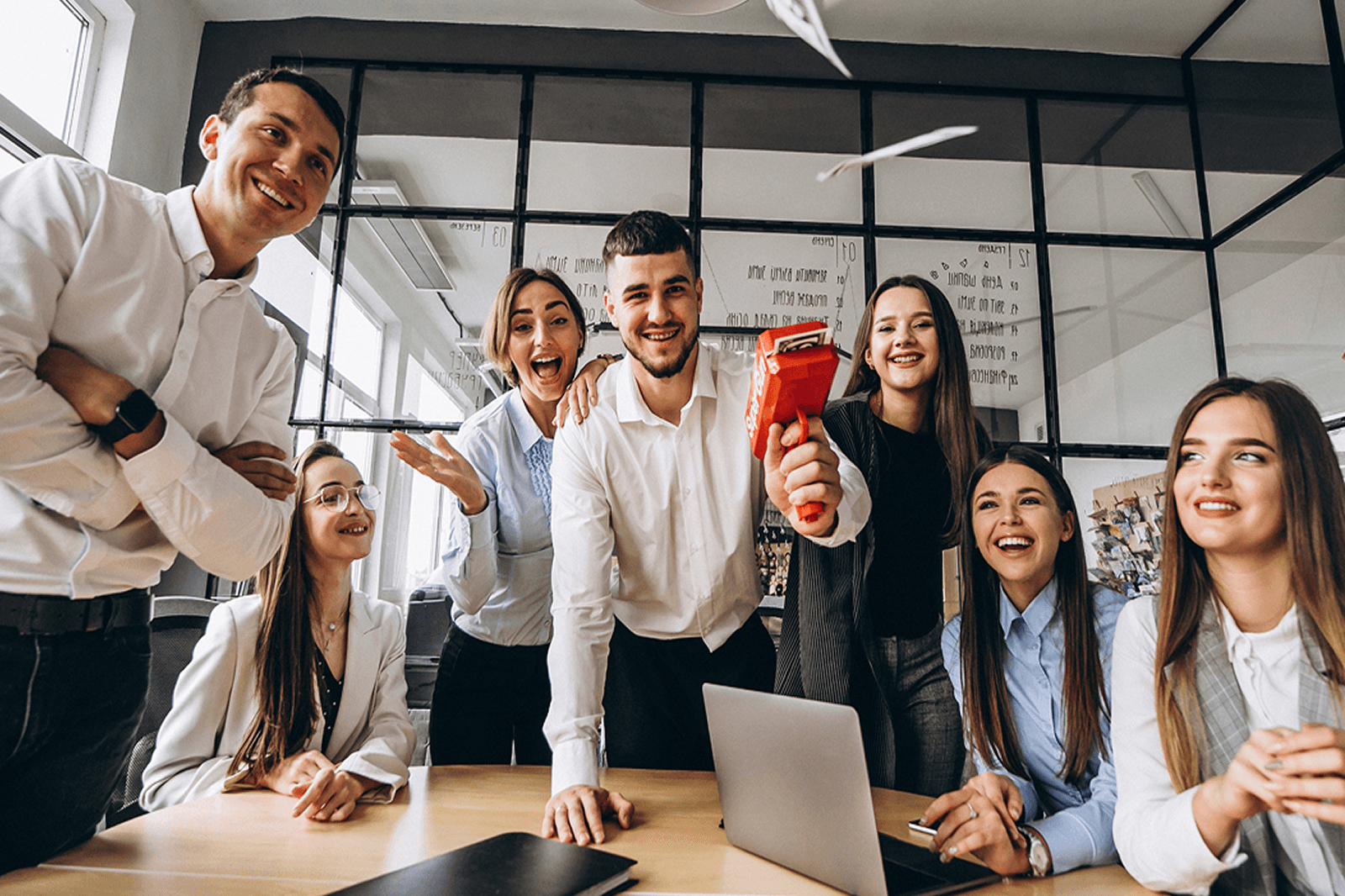 Photo of a celebrating office team with a confetti popper and laptop