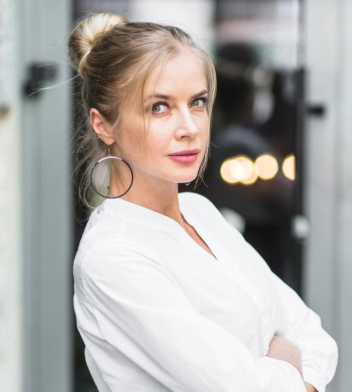 Photo of a woman with a hair bun and hoop earrings looking over her shoulder