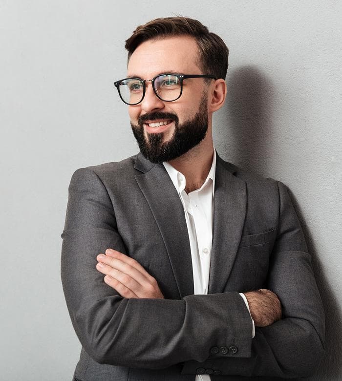 Headshot of a bearded man in glasses and a gray suit with arms crossed